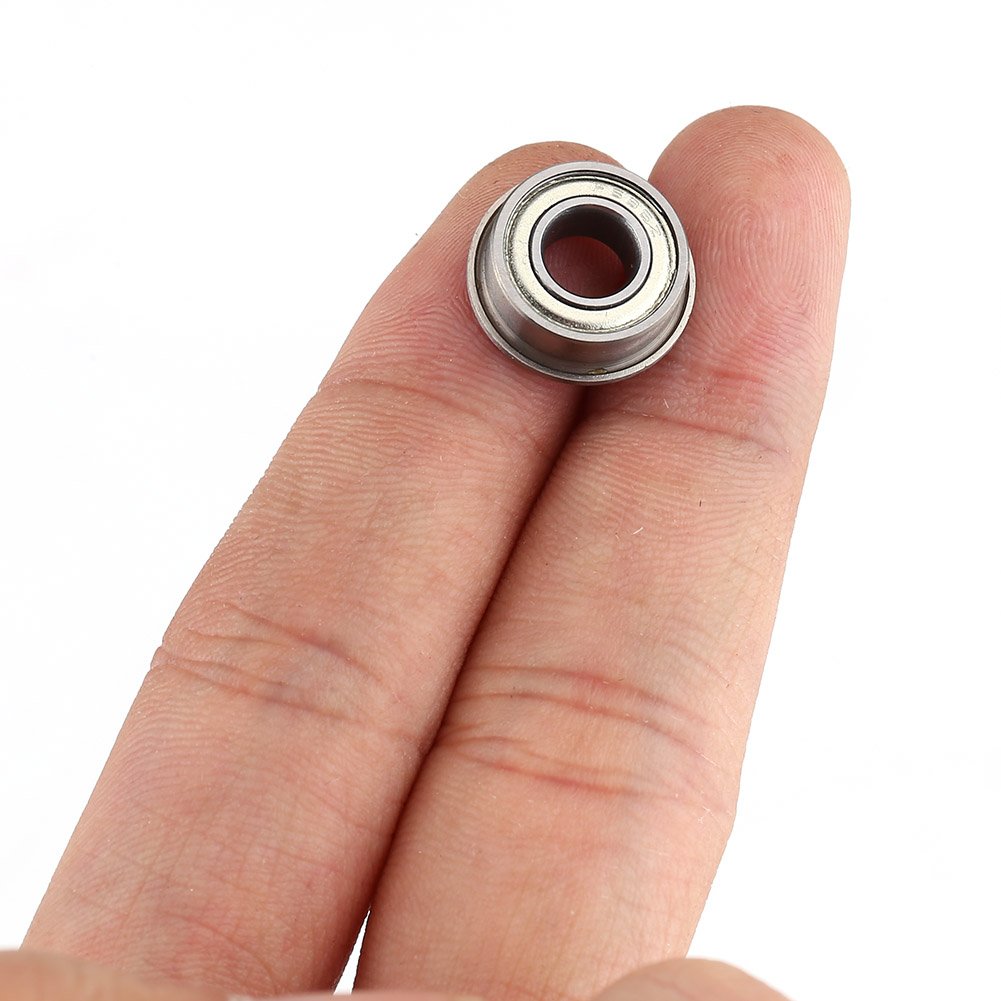 The image shows a miniature flanged ball bearing on fingertips