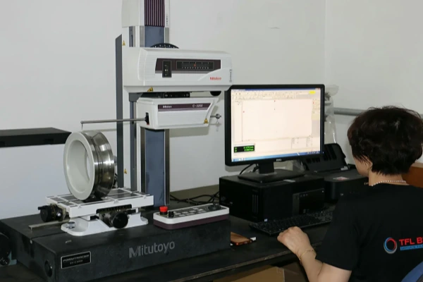 A close-up of a technician conducting a quality inspection on a bearing, signifying TFL's commitment to quality control and material durability.