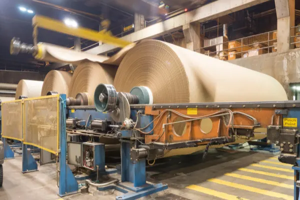 An industrial paper mill machine with large rollers and heavy bearings visible, illustrating the high load environment.