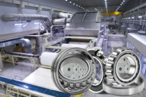 A close-up of a large roller bearing with rollers, illustrating a component built for strength and durability in a paper mill.