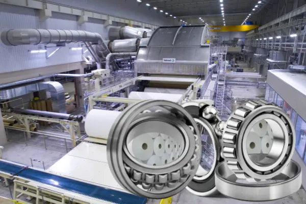 A close-up of a large roller bearing with rollers, illustrating a component built for strength and durability in a paper mill.