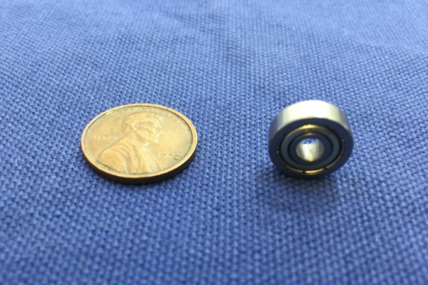A close-up comparison showing the small bore diameter of a miniature ball bearing next to a standard coin.