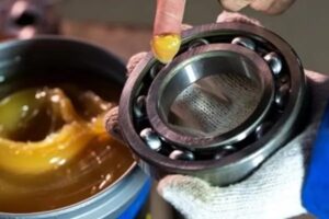 A maintenance technician applying bearing lubrication oil to a rotating industrial machinery component.